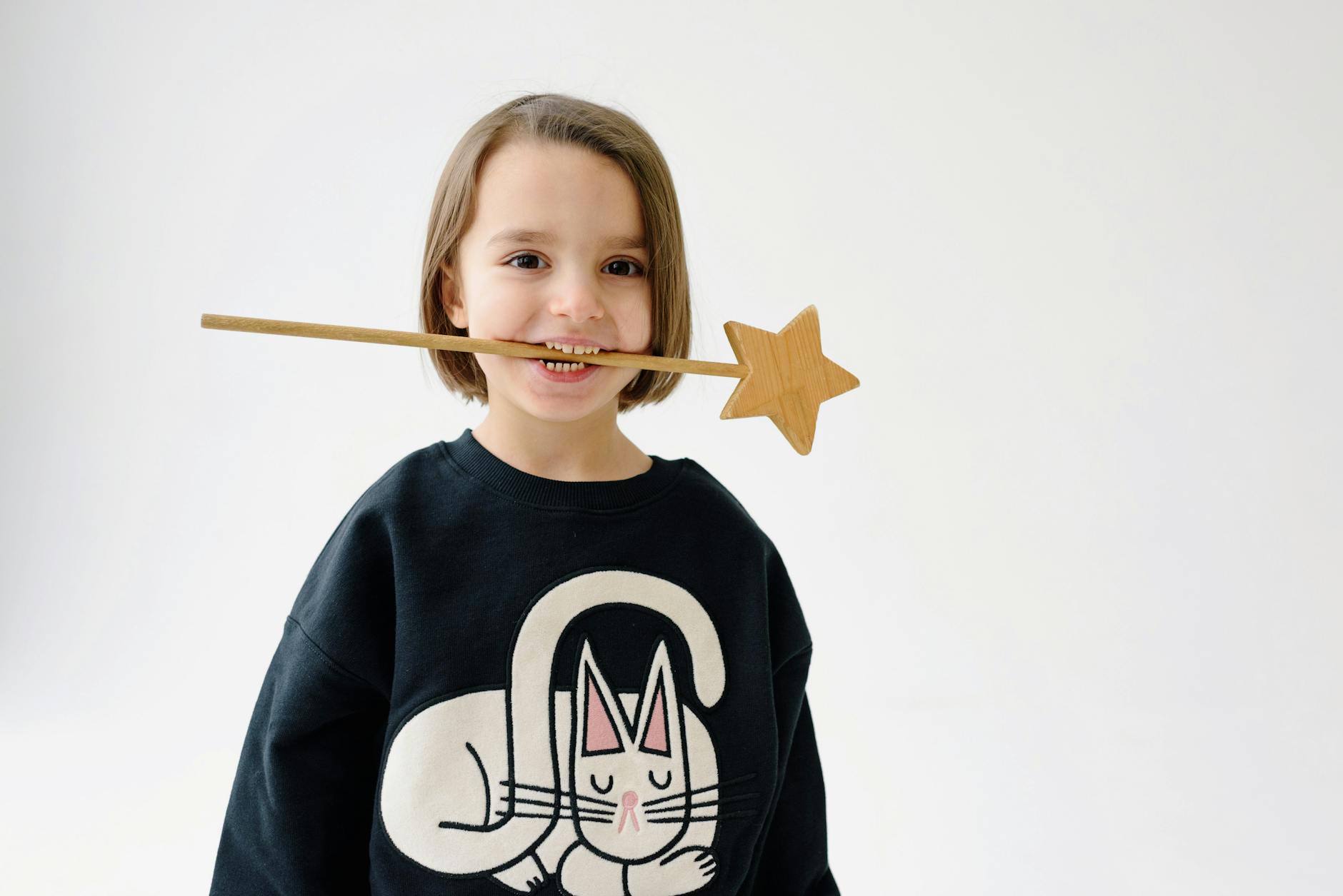 girl standing with a wooden wand on her mouth