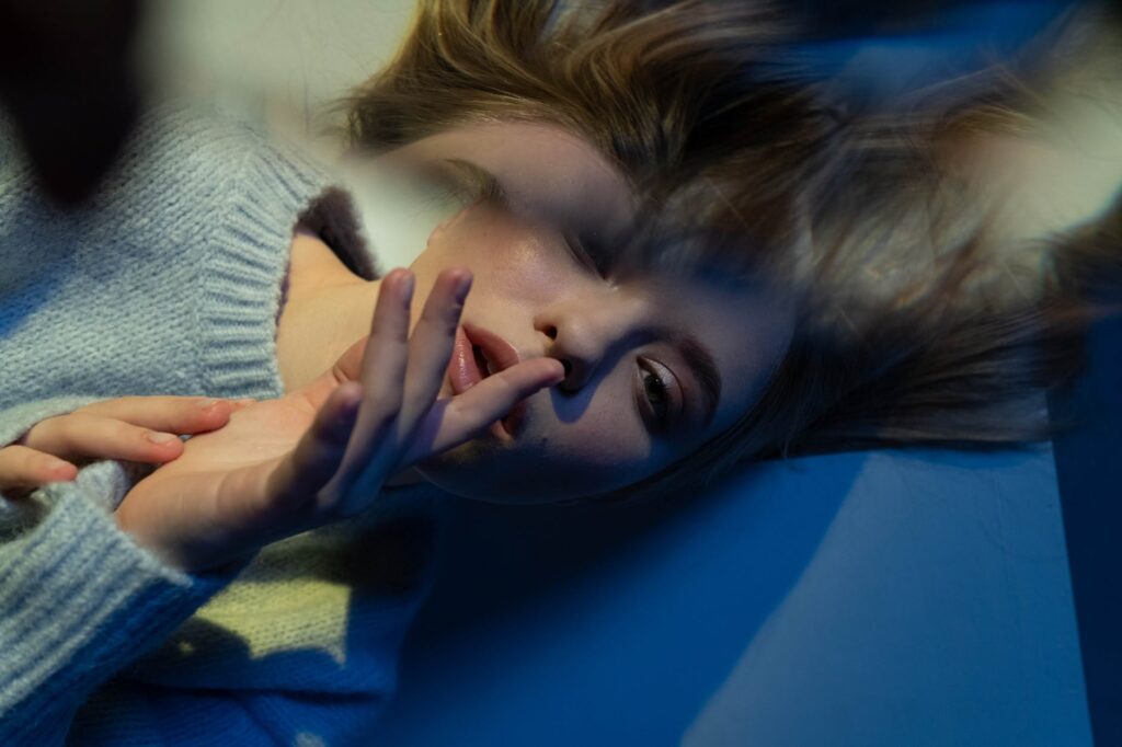 woman in gray sweater lying on blue surface