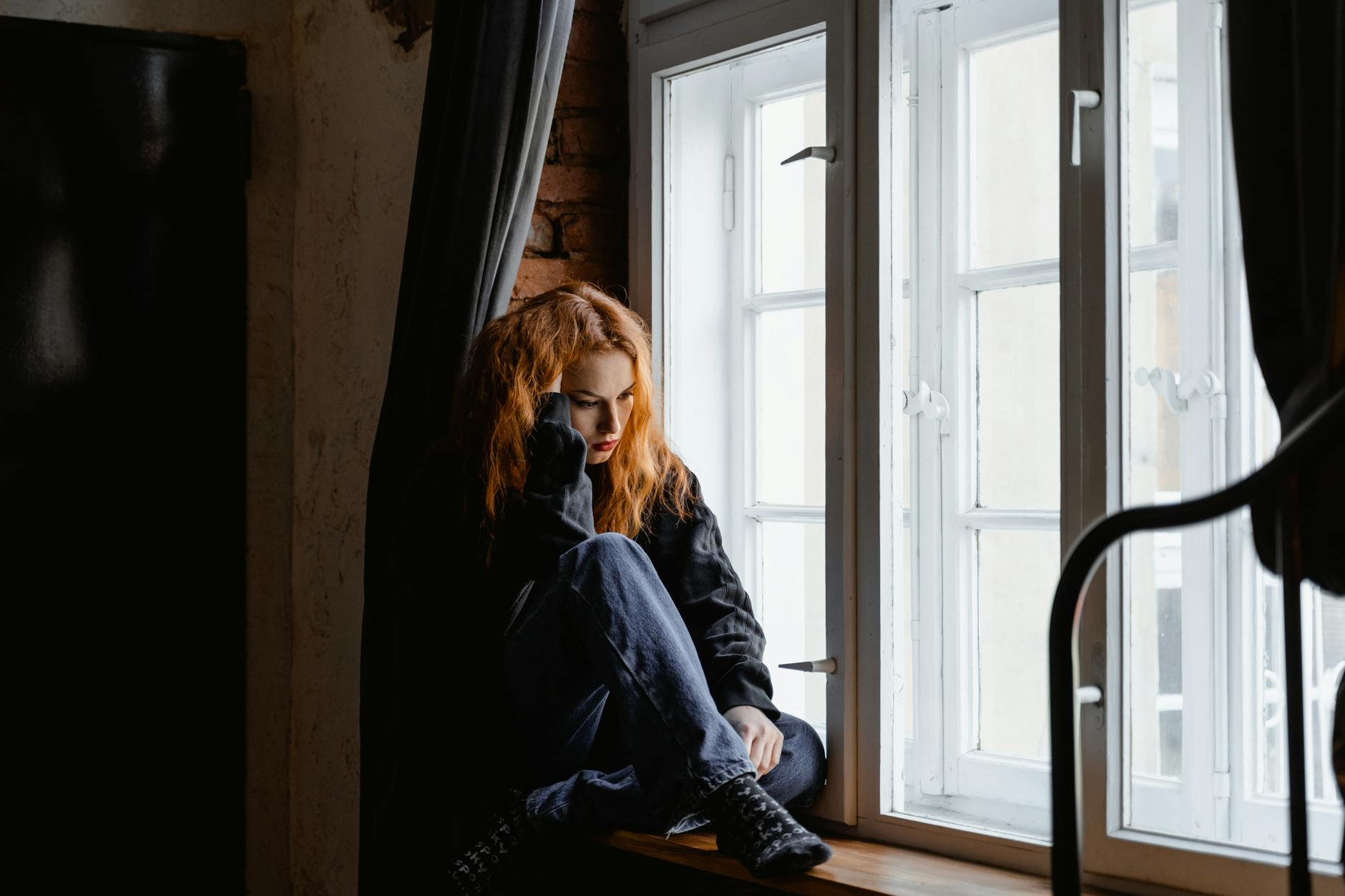 woman in black leather jacket sitting on brown wooden floor